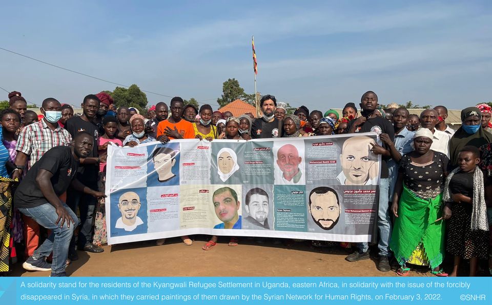 وقفة تضامنية من لاجئين في أوغندا مع مختفين قسرياً في سوريا حملوا رسومات من الشبكة السورية لحقوق الإنسان 3-2-2022
